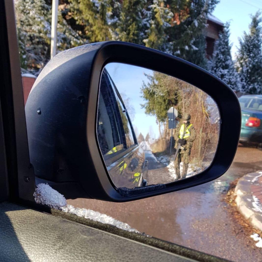 View from car mirror - soldier at road checkpoint